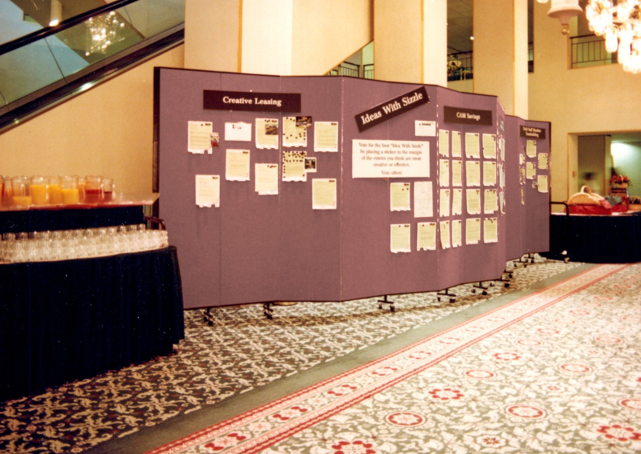 Information for members attending a conference is displayed on portable walls between snack tables