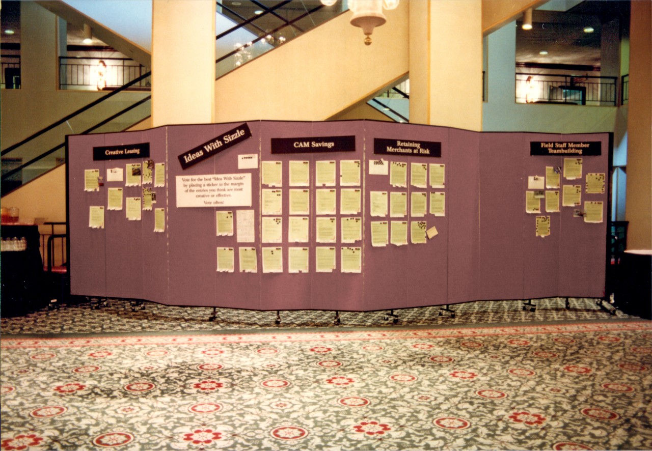 Informational flyers are tacked to a portable room divider outside a conference session