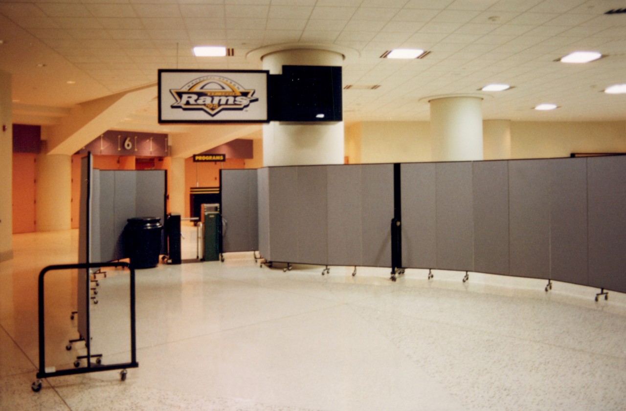 Two room dividers are arranged on each side of a turnstile inside an arena to create a security check point