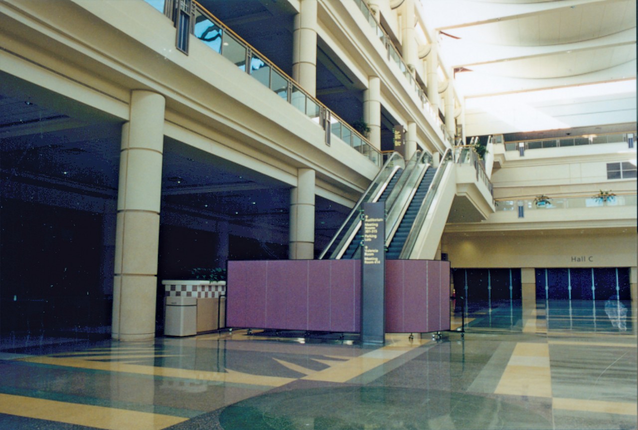 A room divider hides repairs being down on an escalator in a large convention center lobby