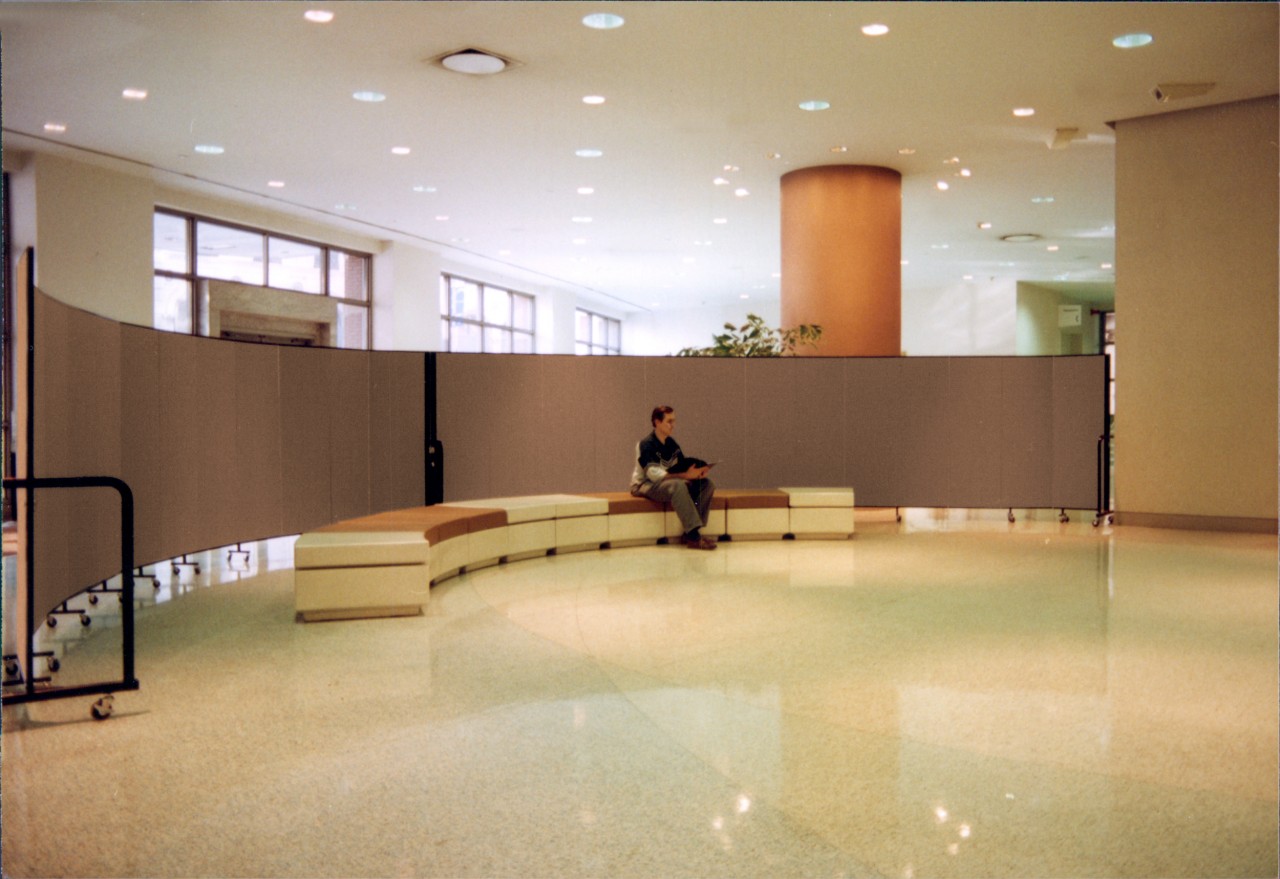 Two tan room dividers attached to each other arrange in an arch in a convention hall lobby