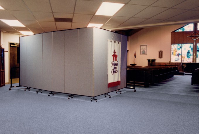 These room divider uses shows a view towards the front of a church with a room divider to the left of the aisle hiding a table and chairs