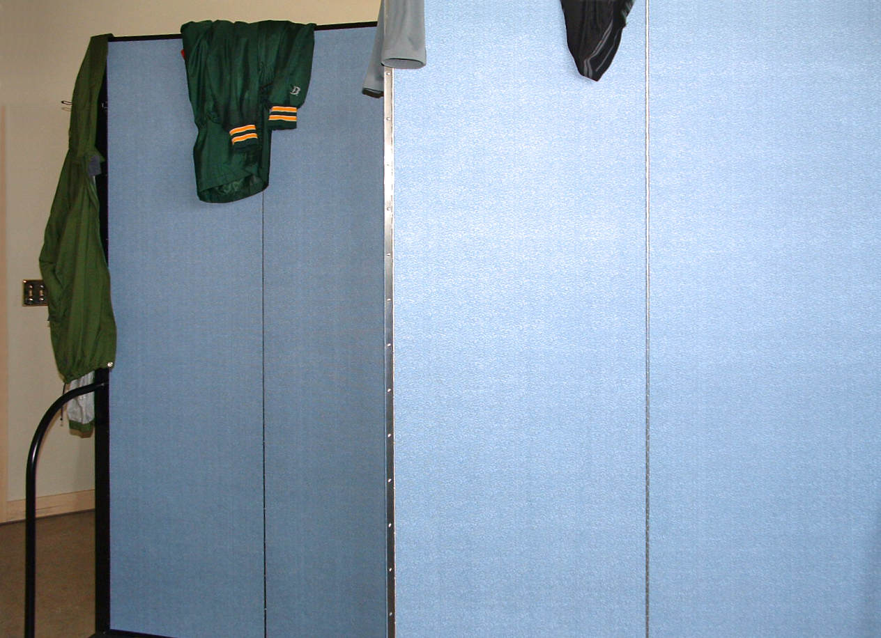 Sports coats draped over the top of a blue room divider