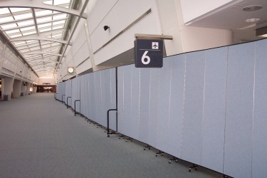 A row of room dividers creates a long wall near gate 6 in an airport terminal