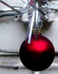 A red ball ornament hangs from a metal pipe A red ornament hanging amongst a grey background