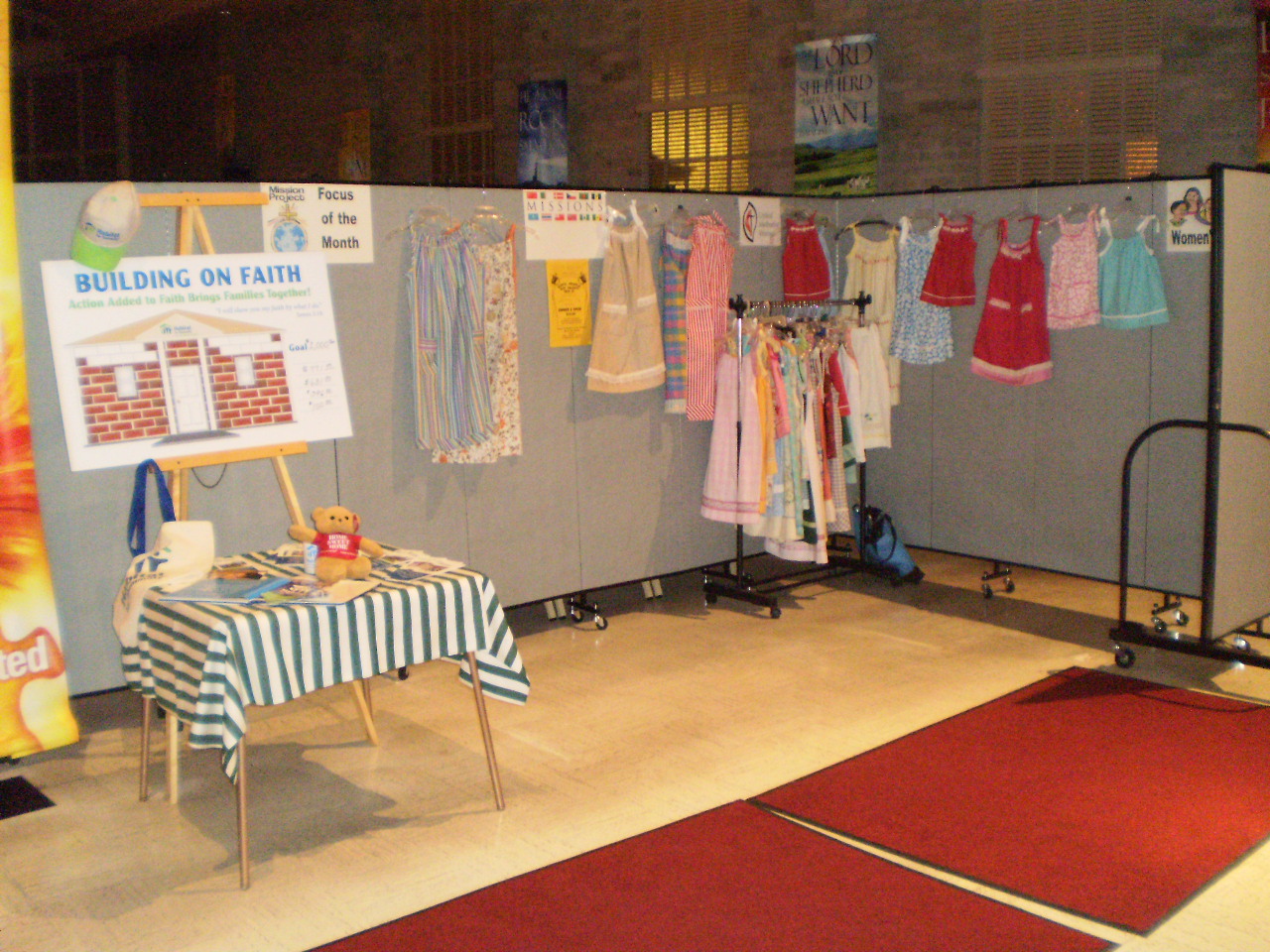 Female dresses are displayed on and around a Screenflex Room Divider in the back of a church entrance