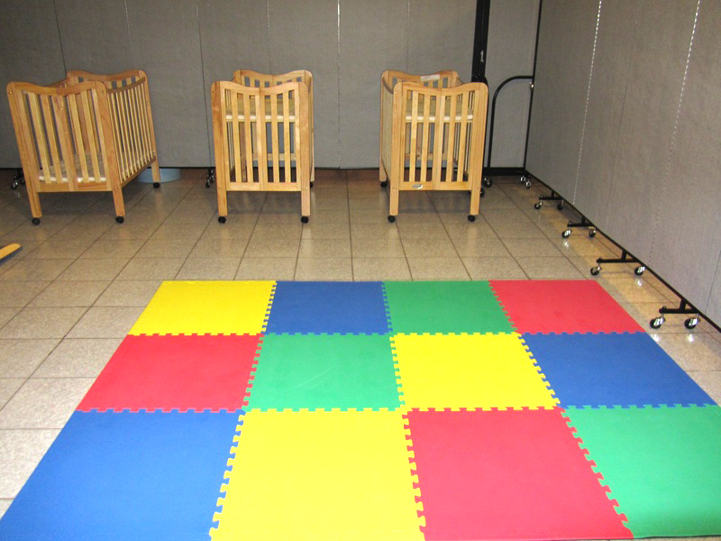3 cribs lay next to an area of Colorsful foam square floor tiles arranged for infant play