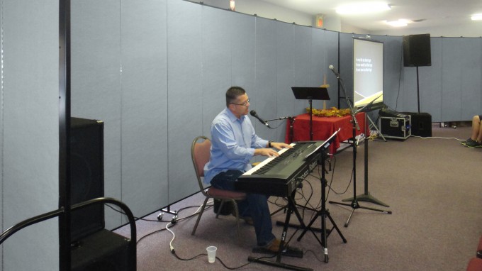 Portable partitions behind a man singing into a microphone while playing a keyboard