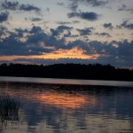 A view of the sunset across the lake behind the hills