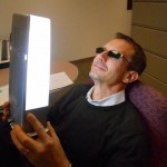 A man in shades holds a "happy light" to his face
