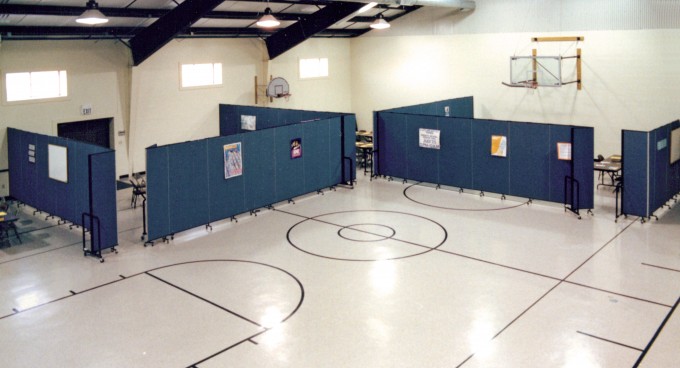 Screenflex Room Dividers are arranged in a gymnasium to create classrooms along the walls