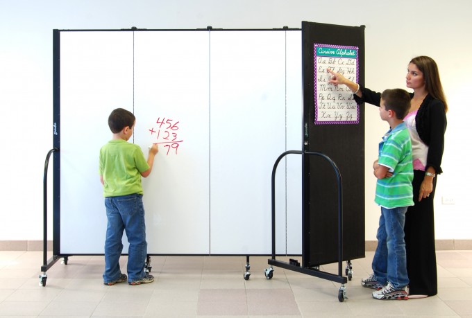 Dual-sided room divider. One side is covered in fabric and the other side is a dry erase board.