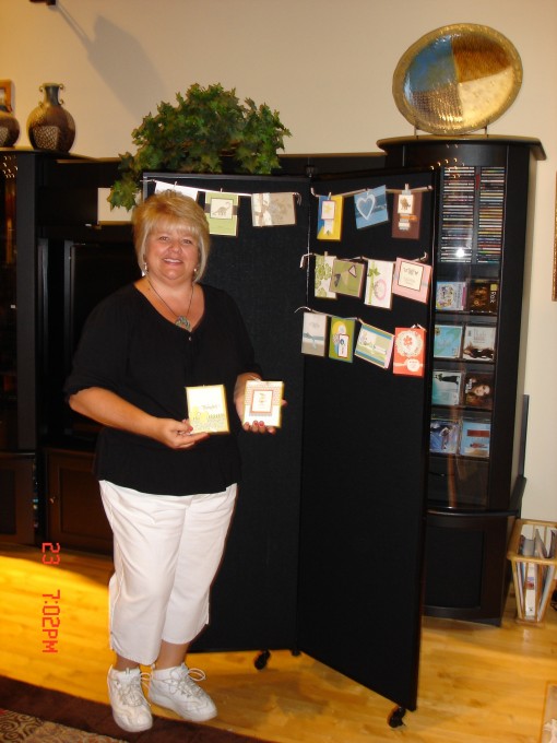 A woman stands next to a black display tower showcasing handmade cards