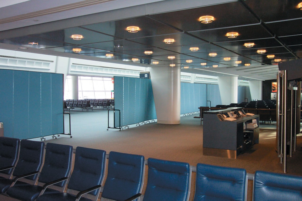 A continuous wall of Screenflex Room Dividers separates a vacant airport terminal from a walkway.