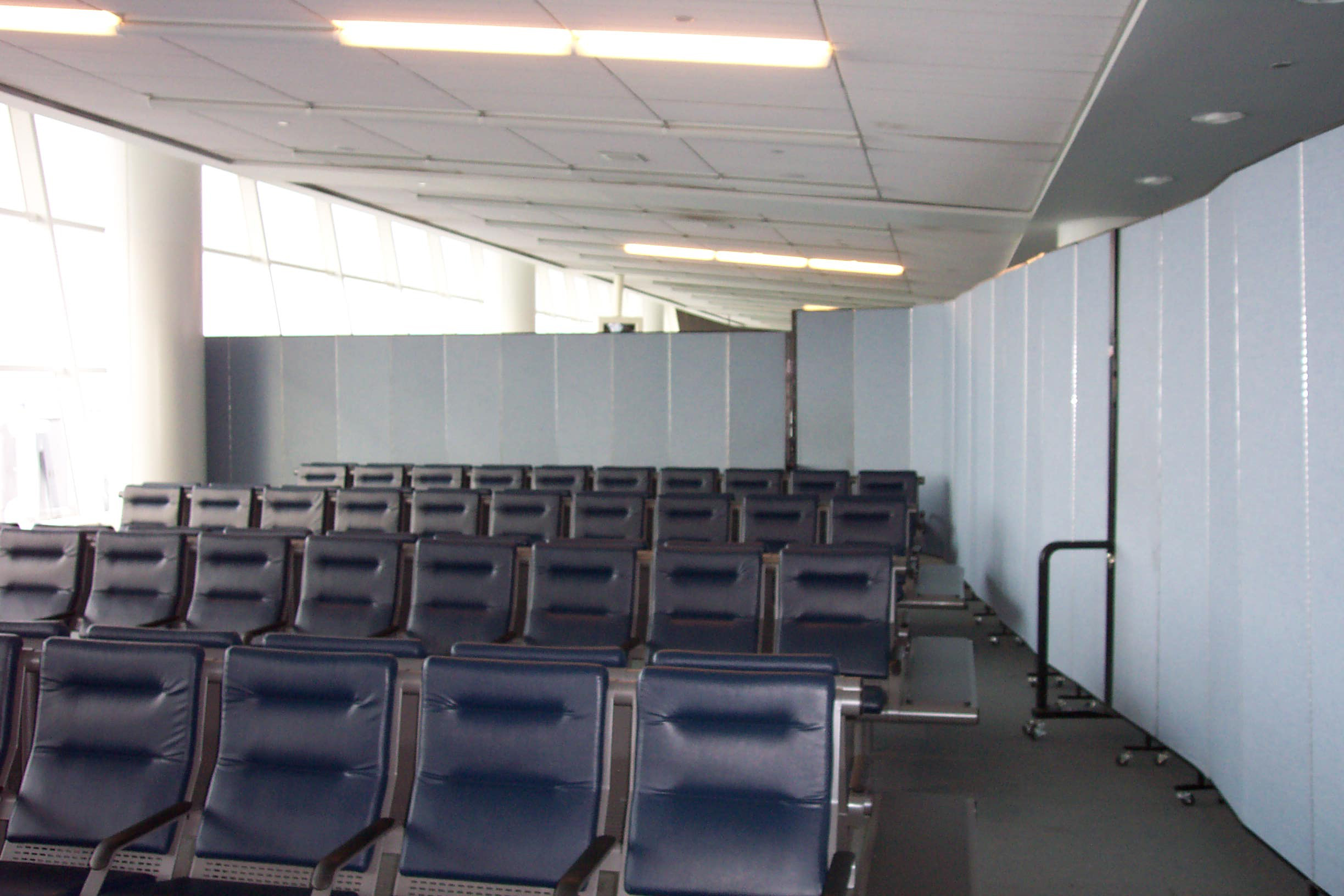 The Benefits of Using Rolling Temporary Walls For Aviation Facility Management & Security | Screenflex Portable Partitions enclosing an airport gate area with portable walls