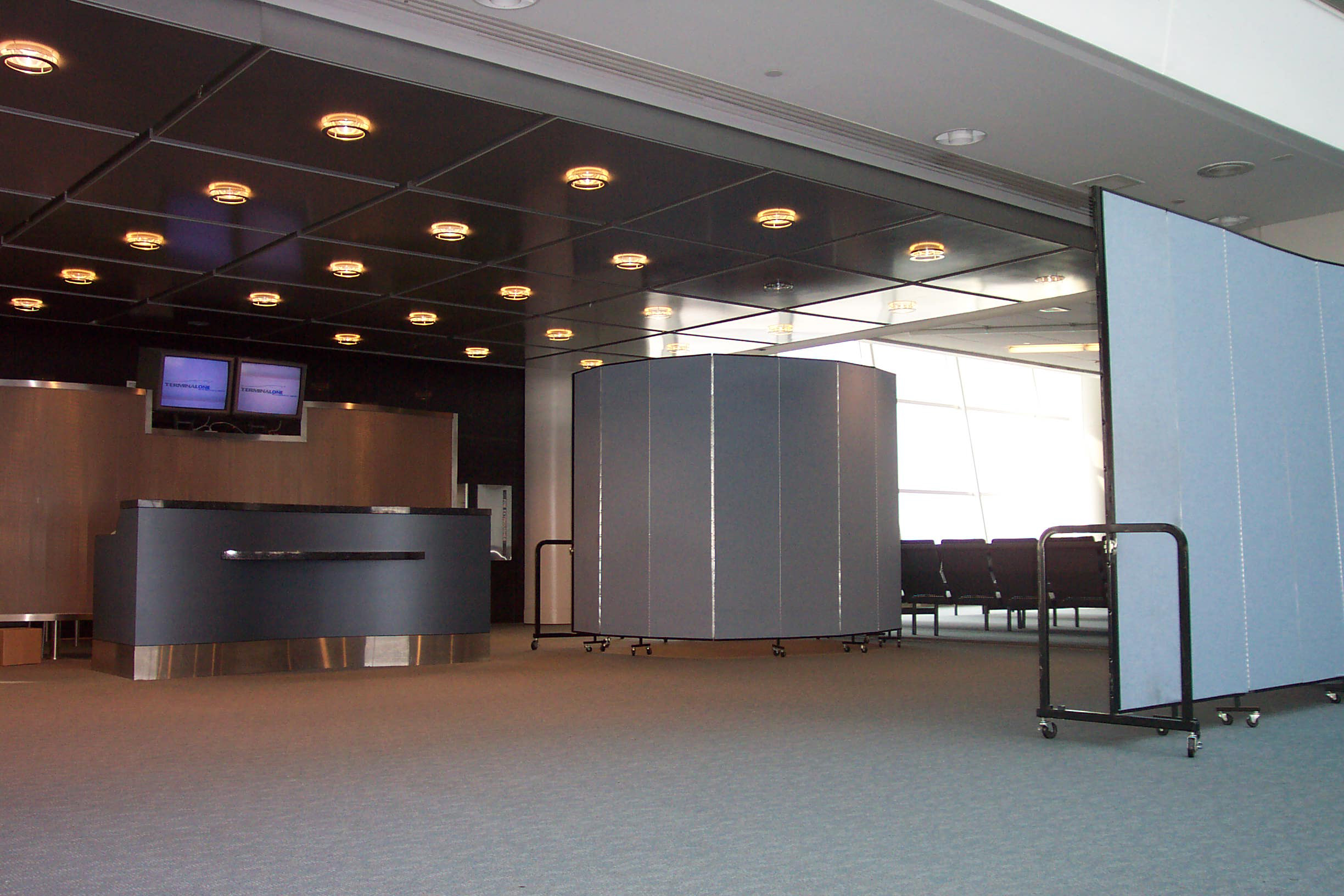 The Benefits of Using Rolling Temporary Walls For Aviation Facility Management & Security | Screenflex Portable Partitions A screening area created at a departure gate