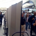 A row of Screenflex Room Dividers separate passengers walking from waiting areas in an airport.