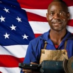 A male in an industrial apron stands in front of the American flag
