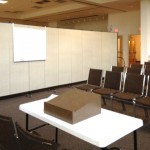 A room divider separates a room into a lecture hall and dining room
