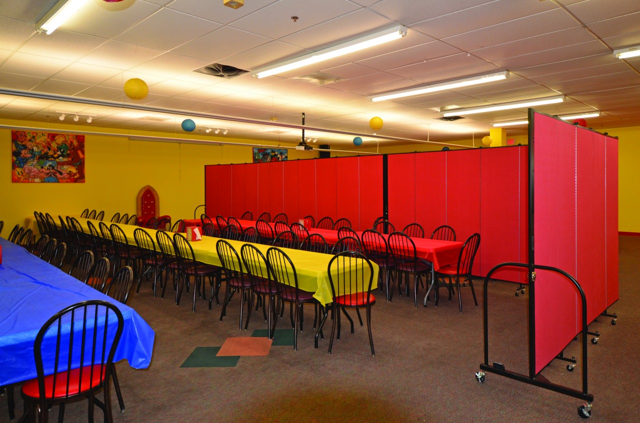 A Colorsful party room is divided into two eating areas with a red Screenflex Room Divider.