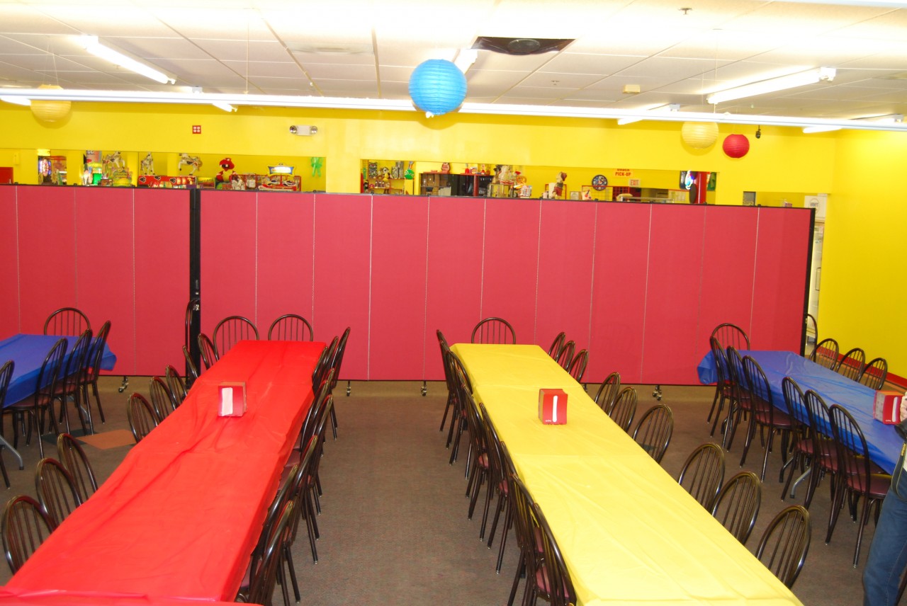 2 connected room dividers create a wall separating a party room from games at an indoor amusement center.