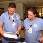 A male and female medical staff review patient records.