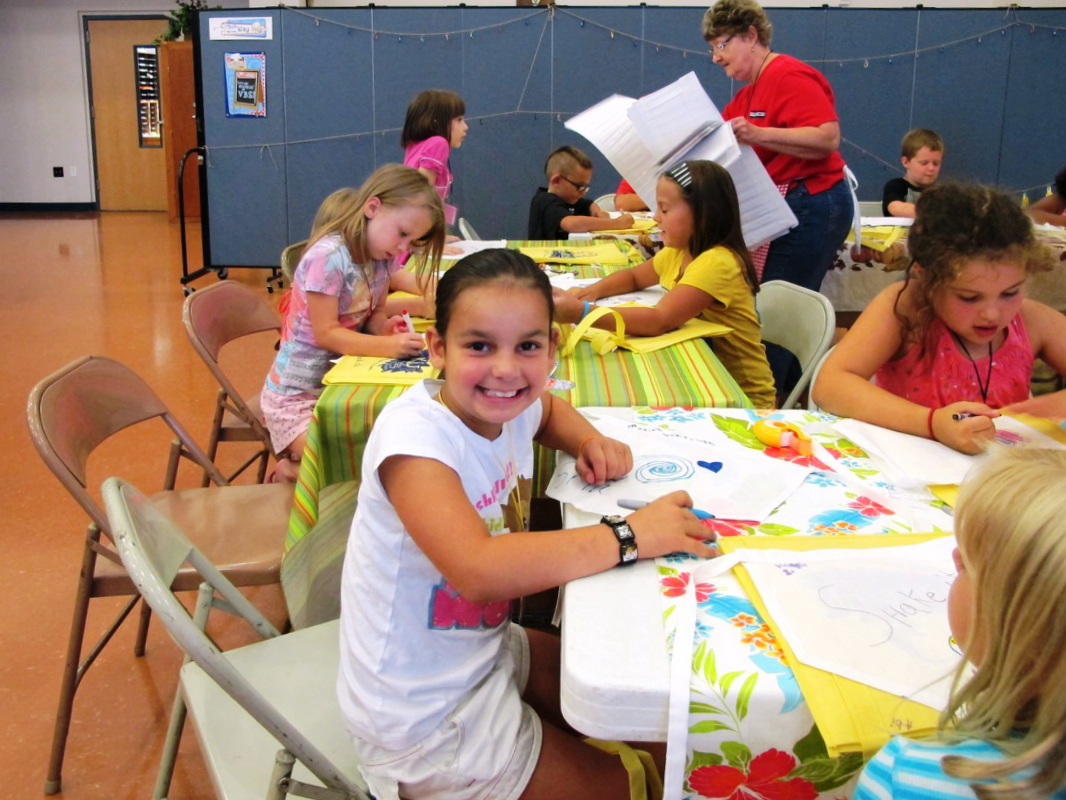 An elementary student stops Colorsing to pose for a picture during craft time at VBS.