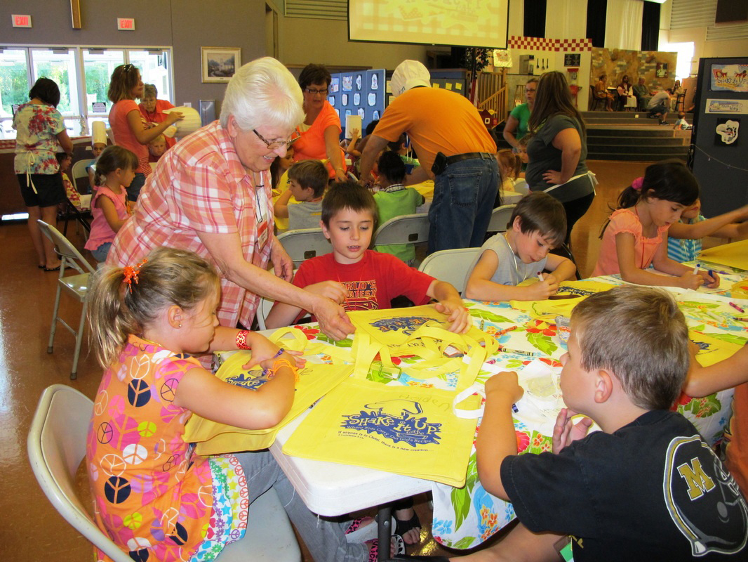 Adult staff assist young VBS students decorate their activitiy bag to be used throughout the week.
