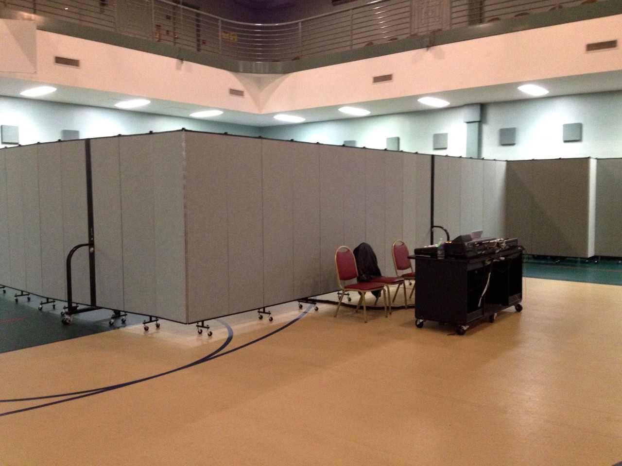 Room dividers separate a church from a meeting room inside a school gymnasium.