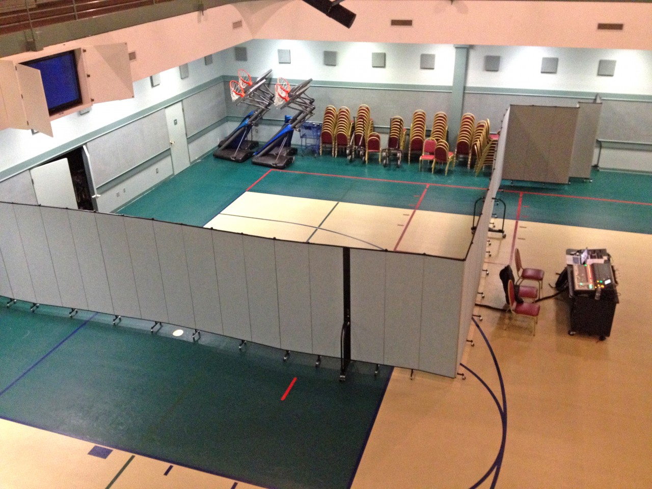 Screenflex Room Divider creates a barrier for storage items and a church in a rented school gym.