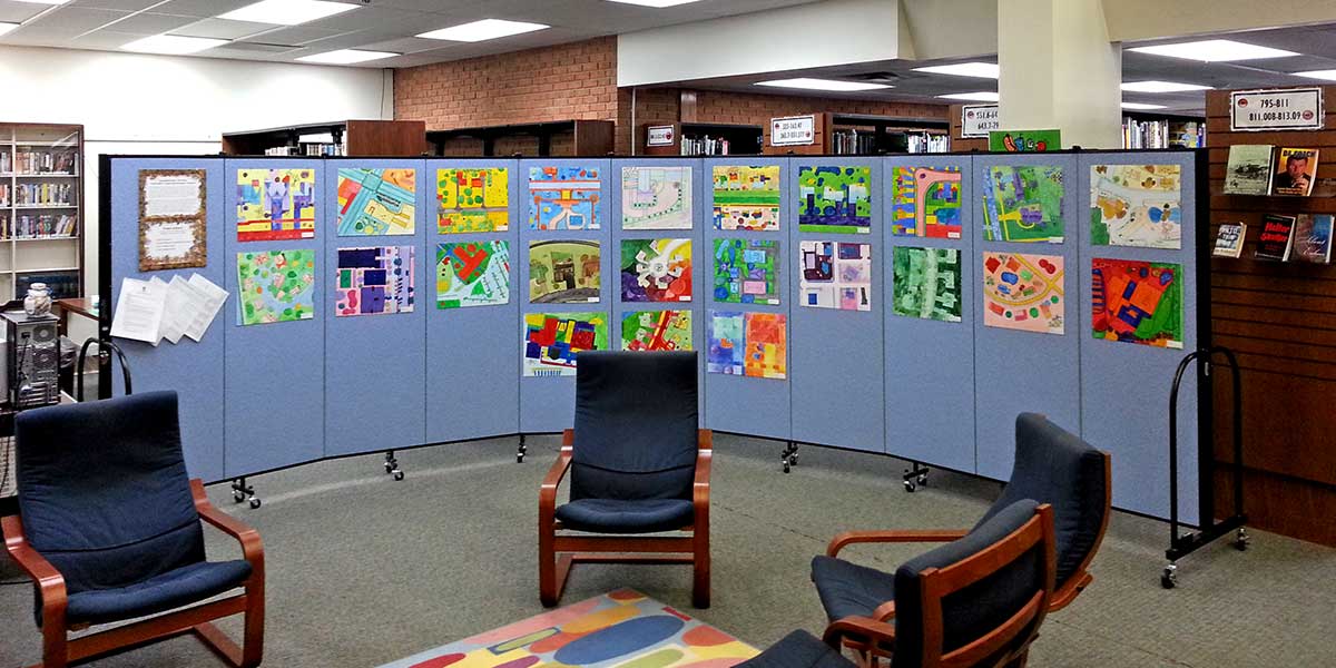 Student artwork is displayed on a room divider panel in a library