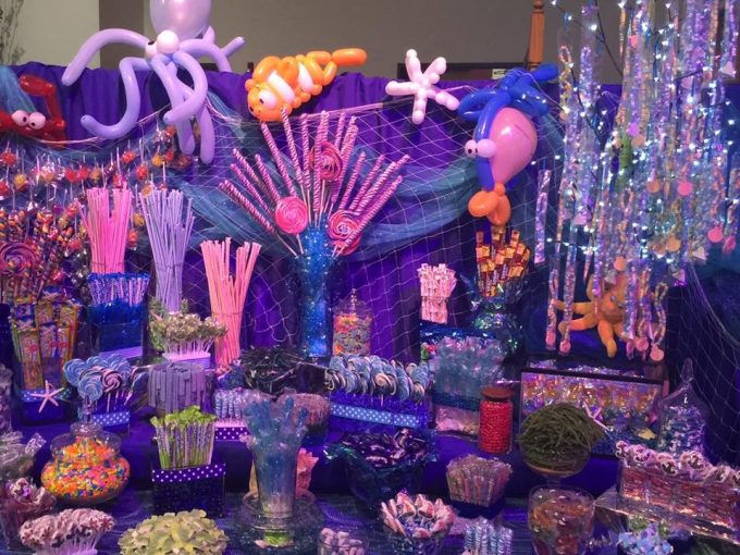 Tables cloths are draped over a potable wall to create the perfect backdrop to a sea themed candy table