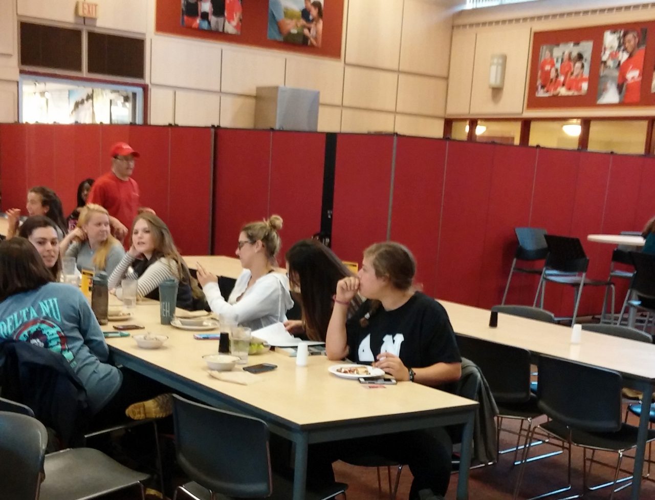 A row of red room partitions divide a cafeteria into two rooms